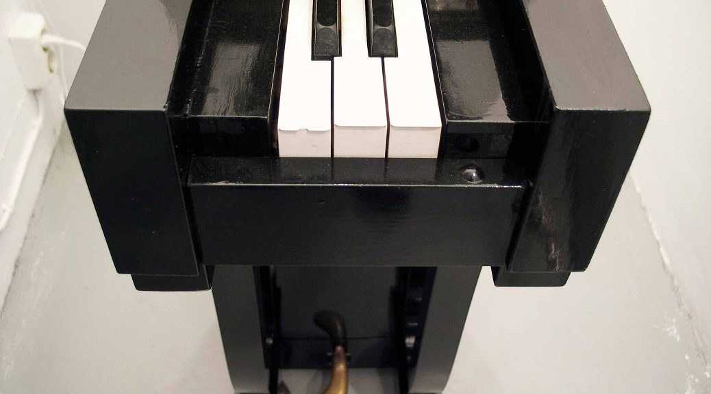 Piano, narrow piano with three white and two black keys, sculpture by Björn Perborg, detail. Piano, smalt piano med tre vita och två svarta tangenter, skulptur av Björn Perborg, detalj.