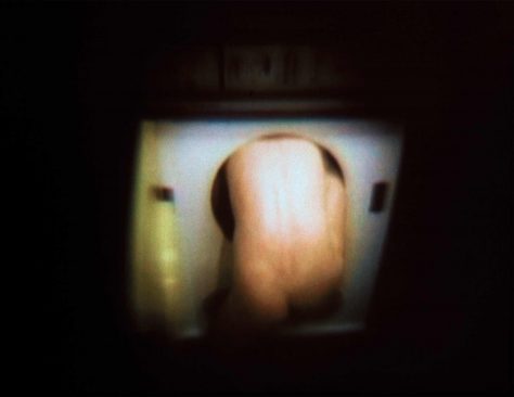 The Tumble-dryer, film still, naked man enters a dryer. Torktumlaren, filmstill, naken man klättrar in i torktumlare.