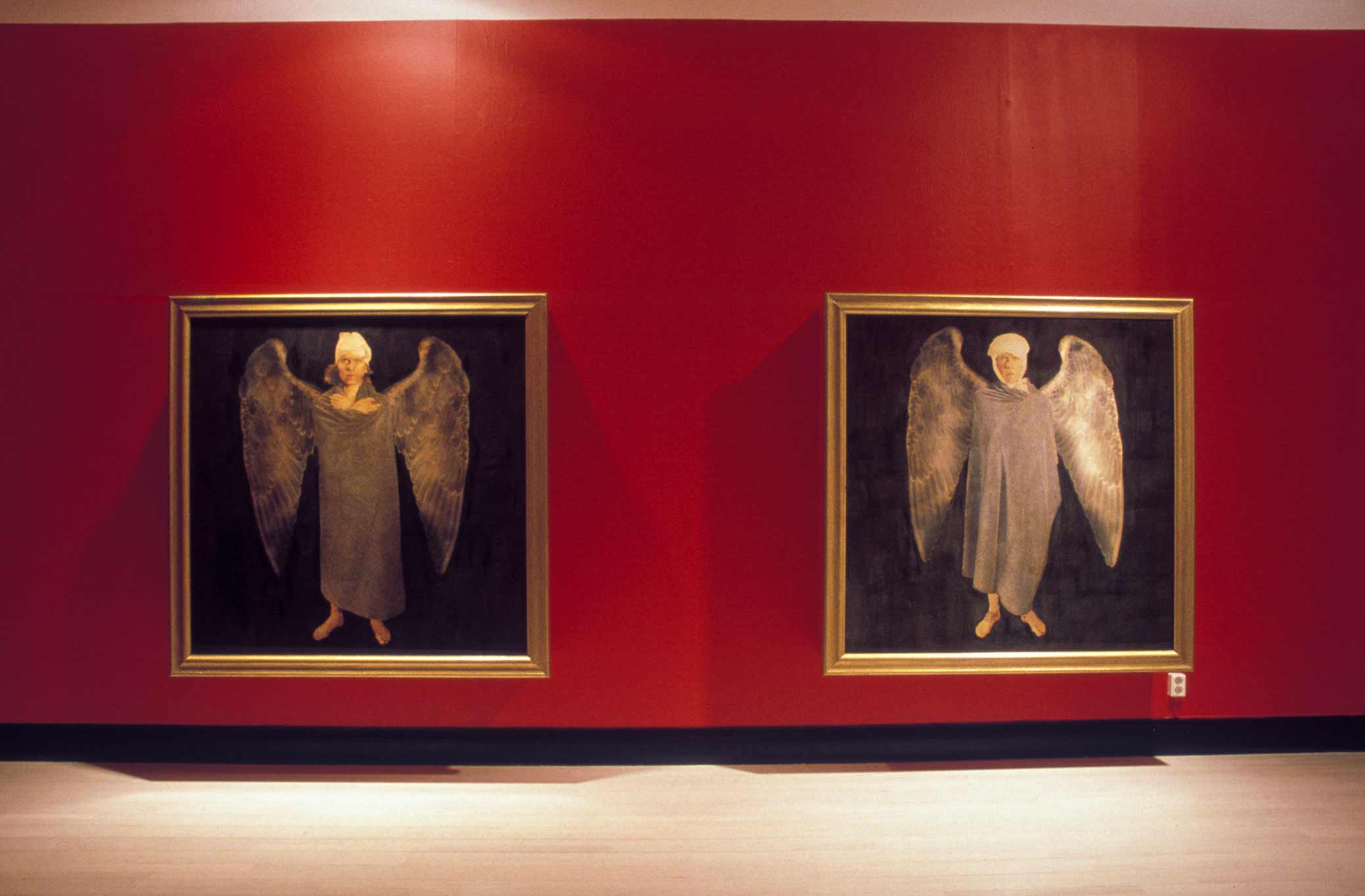 Flygfän, installation with paintings of wounded angels, in a room with red walls. Flygfän, installation med tavlor föreställande skadade änglar, i ett rum med röda väggar.