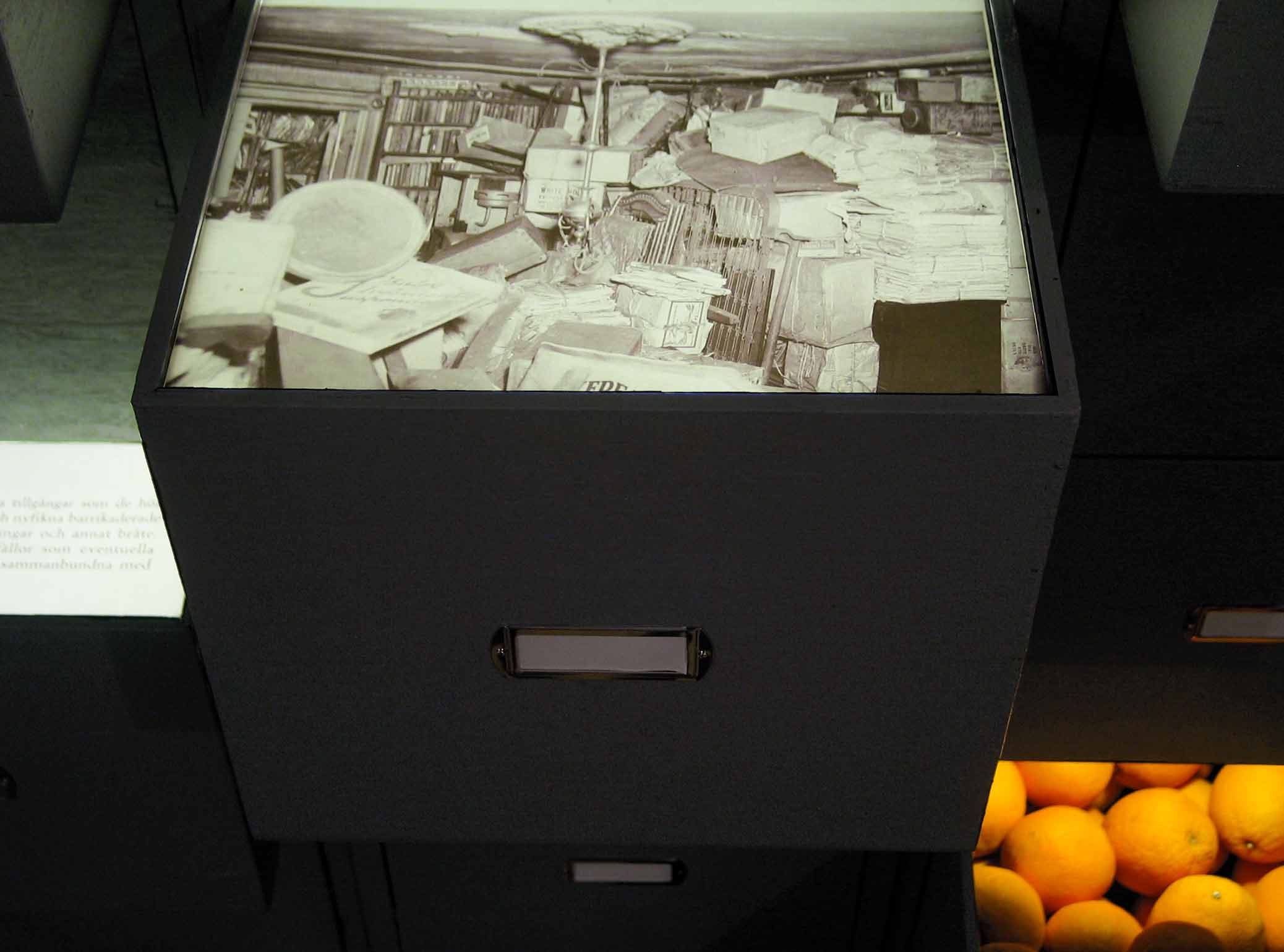Samlarna, installation med arkivskåp på Galleri Box. Detalj, arkivfoto och apelsiner.